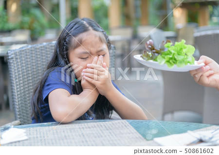 Girl with expression of disgust against vegetables Girl with expression of disgust against vegetables 50861602