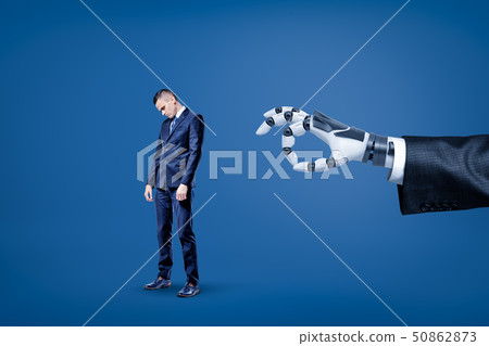 Big robotic hand ready to flick a small sad businessman on blue background 50862873