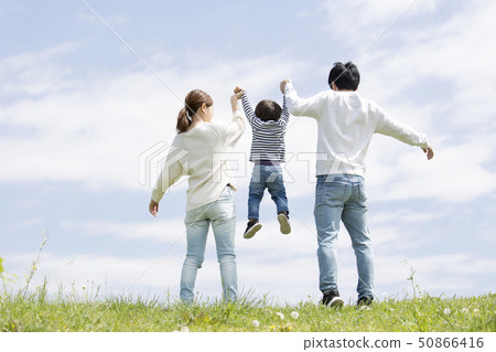 Full length rear view of young family, blue sky background 50866416