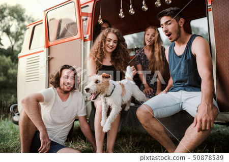 A group of young friends with a dog on a roadtrip through countryside. A group of young friends with a dog on a roadtrip through countryside. 50878589