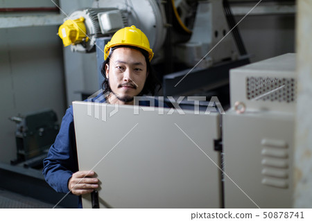 Young Asian engineer use notebook seting to machinery.. 50878741