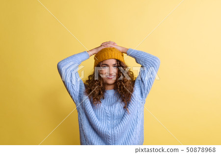 Portrait of a young woman with woolen hat in a studio on a yellow background. Portrait of a young woman with woolen hat in a studio on a yellow background. 50878968