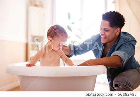 Father washing small toddler son in a bathroom indoors at home. Father washing small toddler son in a bathroom indoors at home. 50882485