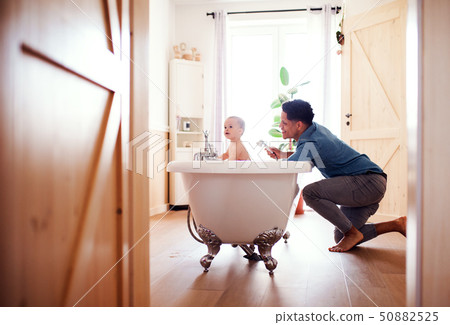 Father washing small toddler son in a bathroom indoors at home. 50882525