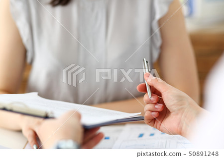Male hand holding silver pen offering some papers for approval terms of cooperation pact 50891248