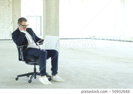 Young businessman with laptop in the big hall Young businessman with laptop in the big hall 50932688