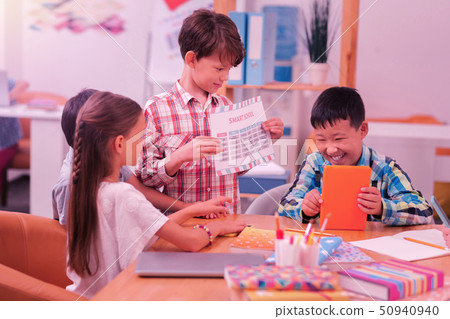 Happy schoolchildren sitting at the desk together. Happy schoolchildren sitting at the desk together. 50940940