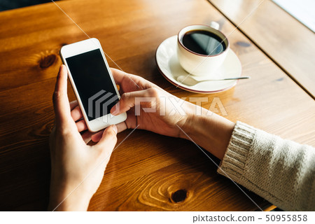 Woman using smartphone on wooden table in cafe 50955858