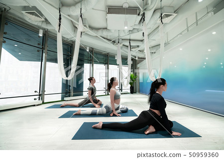 Women and man stretching their legs while doing yoga together 50959360