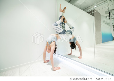 Dark-haired woman doing arm stand near window 50959422