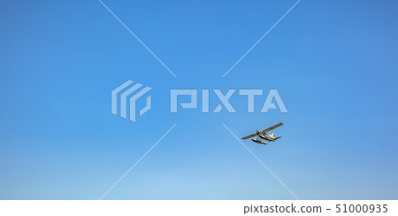 White float plane flying beneath blue sky 51000935