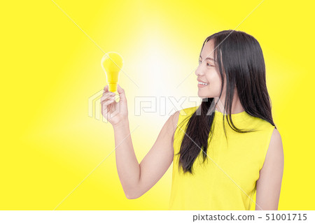 young woman holding yellow light bulb. young woman holding yellow light bulb. 51001715
