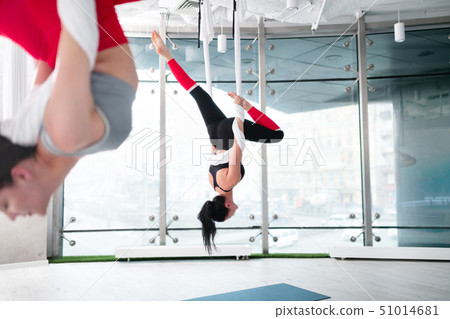 Two women wearing comfy leggings doing aerial yoga together Two women wearing comfy leggings doing aerial yoga together 51014681