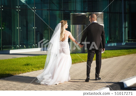 gorgeous bride and groom walking near the modern building 51017271