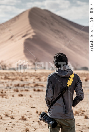 Asian photographer looking at sand dune in desert Asian photographer looking at sand dune in desert 51018169