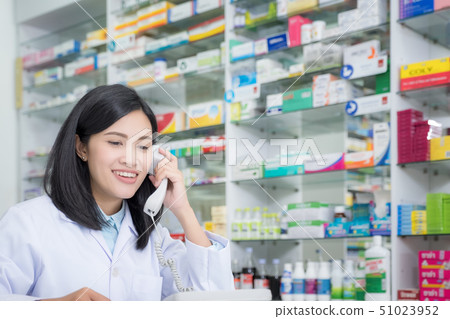 Pharmacy worker talking by phone, Attractive young Pharmacy worker talking by phone, Attractive young 51023952
