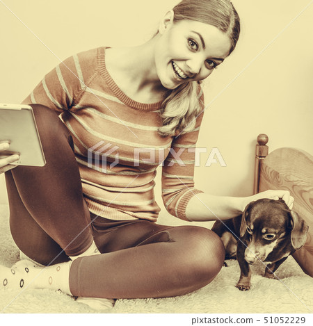 Woman with dog and tablet browsing internet. 51052229