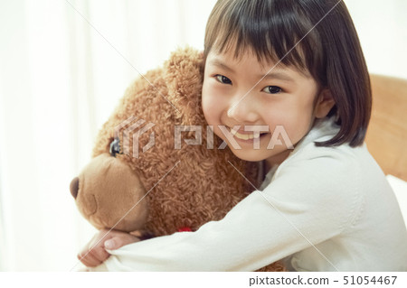Girl playing with a big bear sitting on a chair 51054467