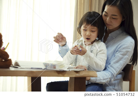 Daughter riding on mother's lap and drawing 51054732