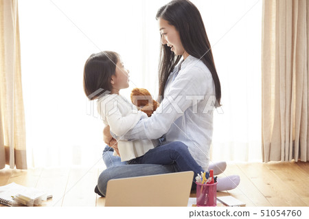 Mother holding a daughter on the floor of the living room 51054760