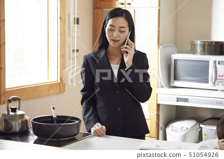 Mother preparing dinner while having phone in the kitchen Mother preparing dinner while having phone in the kitchen 51054926