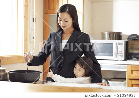 Mother clinging to mother preparing dinner in the kitchen Mother clinging to mother preparing dinner in the kitchen 51054955