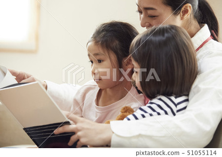 Children having a teacher read and listen on the couch 51055114