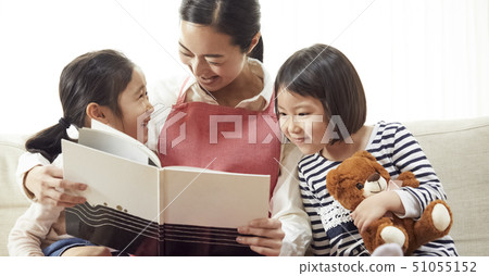 Children having a teacher read and listen on the couch 51055152