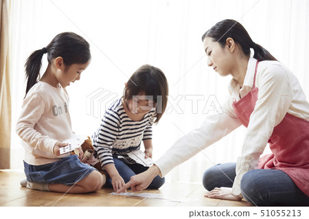 Teachers and children sitting on the floor and playing cards 51055213