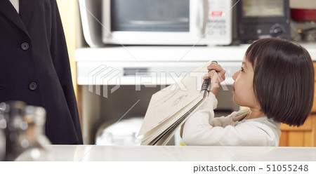 Daughter showing a sketchbook to mother in the kitchen 51055248