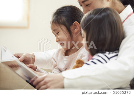 Children having a teacher read and listen on the couch 51055273