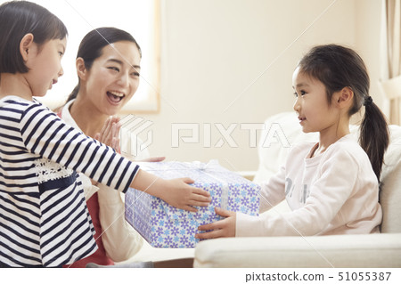 Girl receiving a present from mother and sister on your birthday 51055387