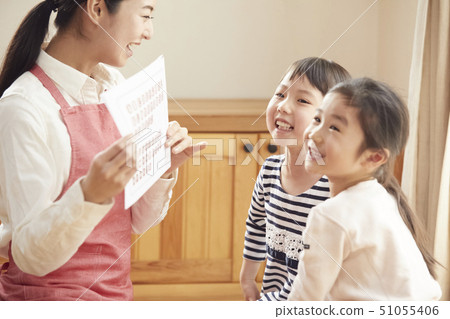 A teacher who takes a problem sitting on the floor and children answering it 51055406