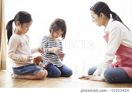 老師和孩子坐在地板上和玩紙牌 老師和孩子坐在地板上和玩紙牌 51055429