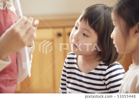 A teacher who takes a problem sitting on the floor and children answering it 51055448