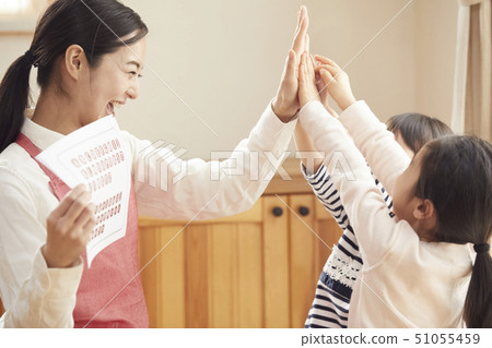 A teacher who takes a problem sitting on the floor and children answering it 51055459