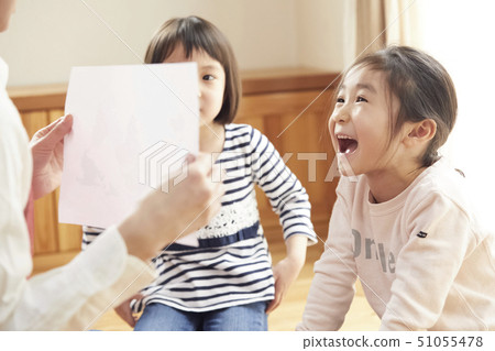 A teacher who takes a problem sitting on the floor and children answering it 51055478