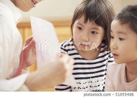 A teacher who takes a problem sitting on the floor and children answering it A teacher who takes a problem sitting on the floor and children answering it 51055486