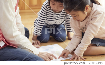 A teacher who takes a problem sitting on the floor and children answering it A teacher who takes a problem sitting on the floor and children answering it 51055498