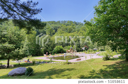 Clean pool with wooden benches, sun loungers and a 51058611