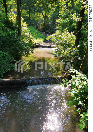 A fast river flowing with large water currents aga A fast river flowing with large water currents aga 51059035