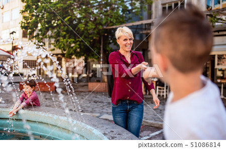 Young mother with two small children having fun outdoors in town. 51086814