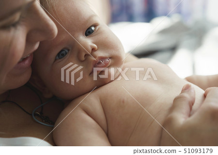 Mother with her newborn son lay on the bed in the rays of sunlight 51093179