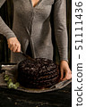 Woman cuts chocolate cake close. Dark tones 51111436