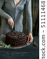 Woman cuts chocolate cake close. Dark tones 51111468