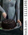 Woman cuts chocolate cake close. Dark tones 51111498