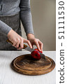 Woman cuts red apple on board close 51111530