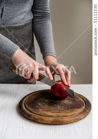 Woman cuts red apple on board close 51111530