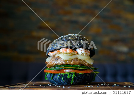 Black burger with prawns on wooden board 51111657