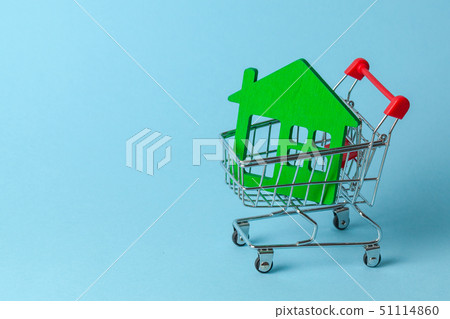 Shopping cart and house on a blue background. Buying and selling real estate. Copy space for text. Shopping cart and house on a blue background. Buying and selling real estate. Copy space for text. 51114860